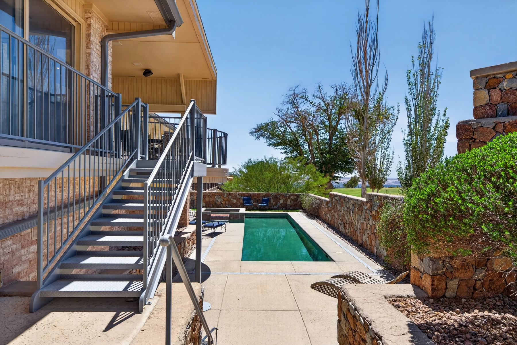 Pool and rear exterior with stone walls and course views